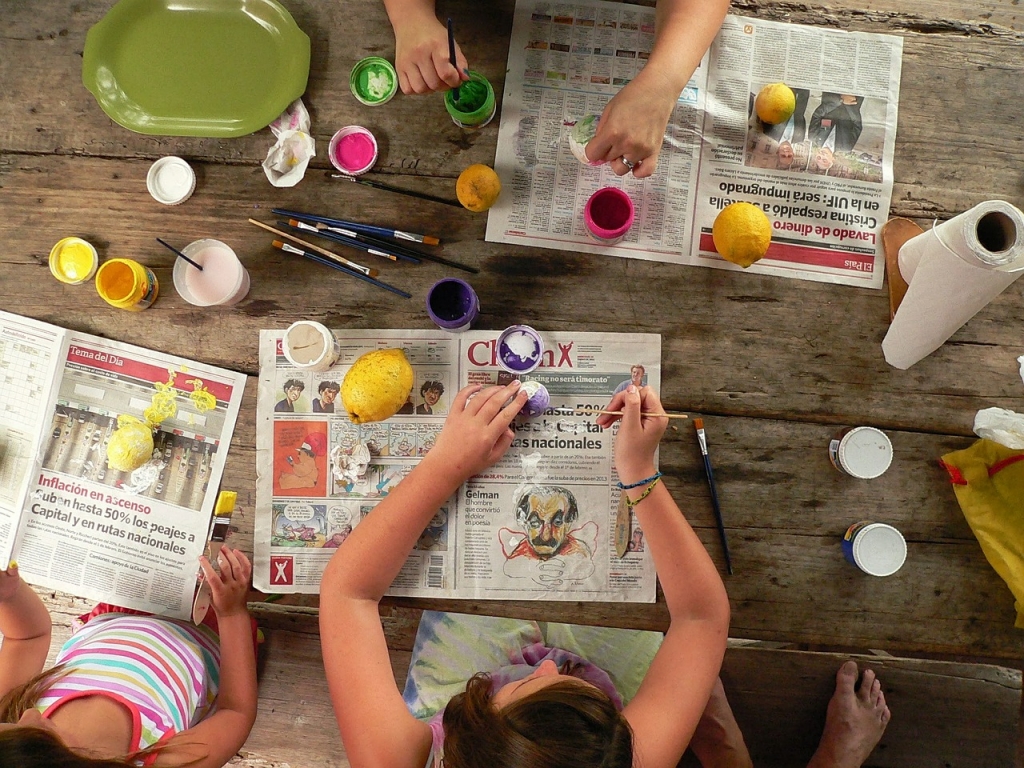 Nens pintant sobre la taula protegida amb paper de diari.